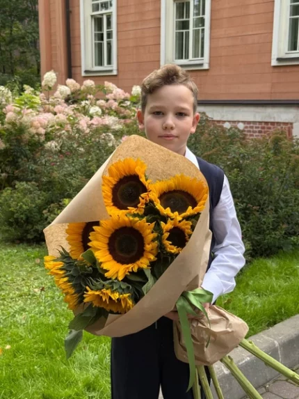 Яркий букет подсолнухов в руках мальчика, праздничное настроение, цветы для особого случая.