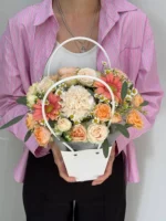 Связанный с цветами букет в корзине, подаренный женщине.