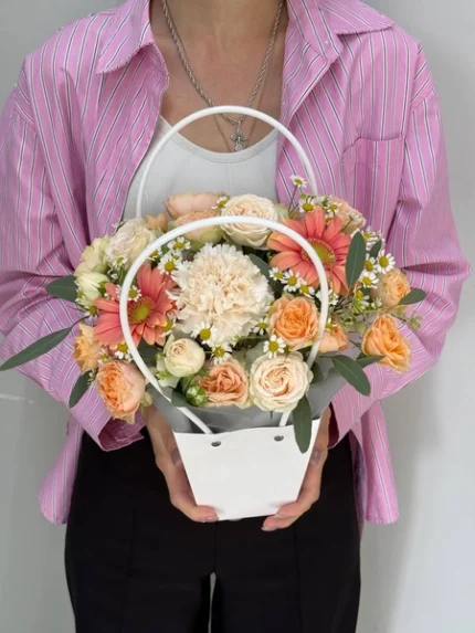 Связанный с цветами букет в корзине, подаренный женщине.