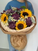 Свежий букет с подсолнухами и хризантемами в крафт-обертке для подарка.