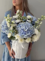 Нежный букет из голубых и белых цветов в подарочной коробке, идеальный для особого случая.