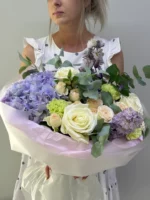 Свежий букет из роз и гортензий в стильной упаковке, идеально для праздничных мероприятий.