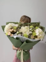 большой букет цветов с белыми и розовыми цветами в зеленой упаковке.