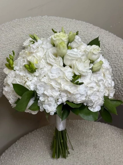 Белый свадебный букет из гортензии и роз с зеленью, идеальный для торжественных мероприятий.
